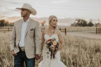 a rustic groom’s look with navy jeans, a white shirt, a neutral linen blazer, a neutral hat and a belt with a large buckle