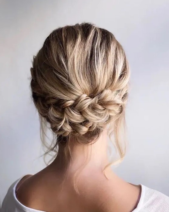 a rustic low updo with a double braid and some locks down is a stylish idea for a rustic or boho wedding