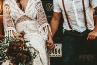 a rustic meets boho groom’s look with a white linen shirt, black jeans, brown suspenders, brown shoes and a hat