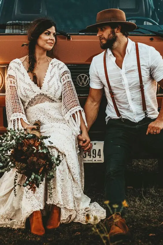 a rustic meets boho groom's look with a white linen shirt, black jeans, brown suspenders, brown shoes and a hat
