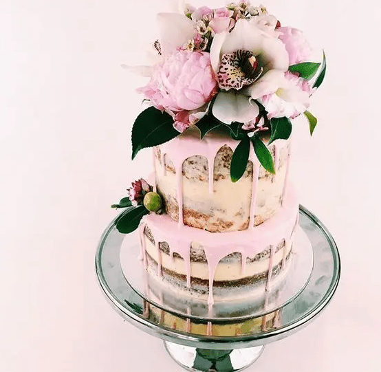 a semi naked pink drip wedding cake with flowers and greenery is a lovely idea for a spring or summer wedding