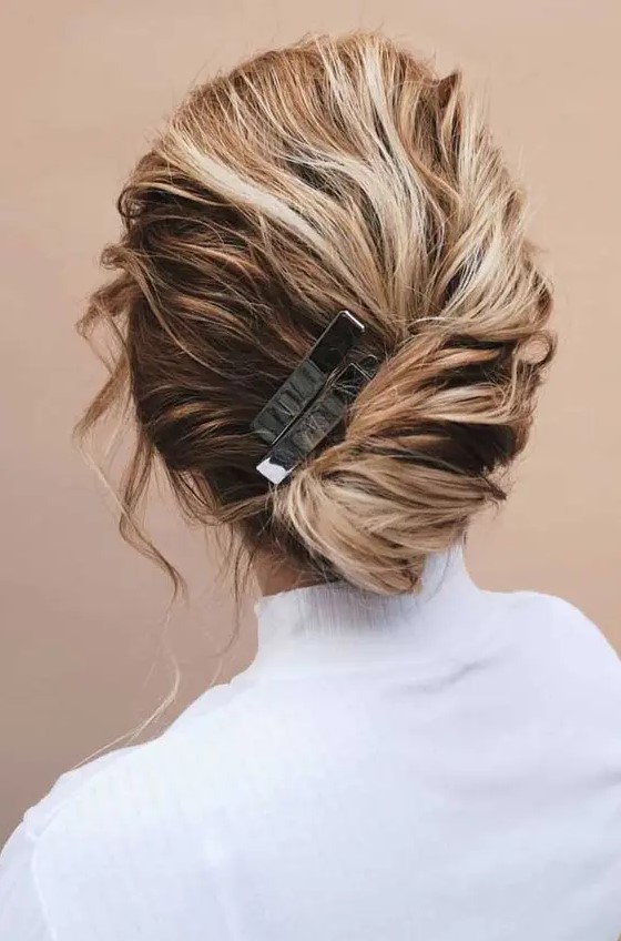 a simple and casual hairstyle - a low updo with twisted hair and a volume on top, with locks framing the face