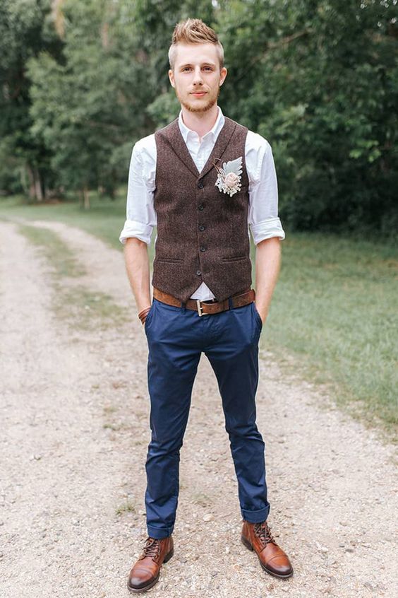 a simple rustic groom's look with a white shirt, navy pants, a brown woolen waistcoat, a brown belt and shoes