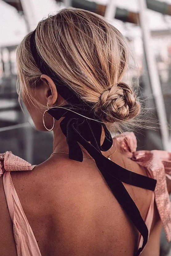 a small braided low bun with a bit of volume on top accented with a black velvet ribbon and a bow is a lovely and girlish idea