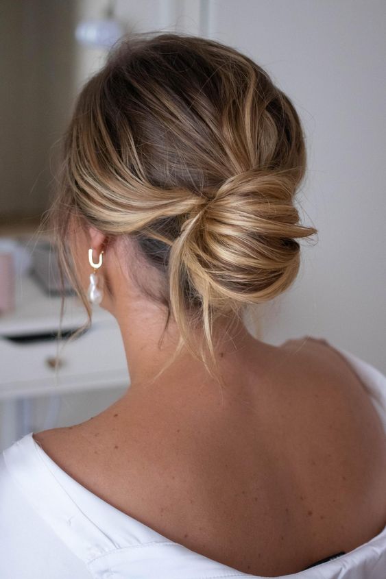 a stylish and chic messy chignon with waves on top and some locks down is a beautiful and elegant idea for a wedding