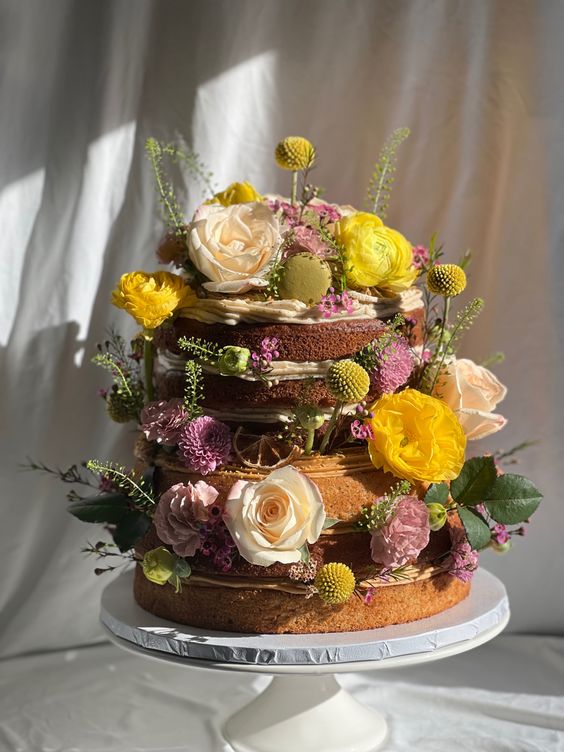 a super cool naked wedding cake decorated with bold yellow and pink blooms, greenery and billy balls is awesome for spring