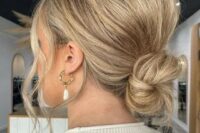 a super messy and cool wedding low ballerina bun with a messy bump on top and face-framing locks is wow