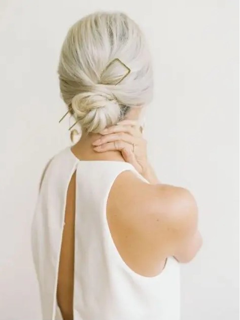 a twisted low bun with a volume on top and a statement hair pin for a minimalist look