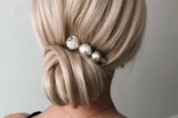 a very elegant low bun with a volume on top and a pearly hairpin is a stylish idea for bride looking for elegance