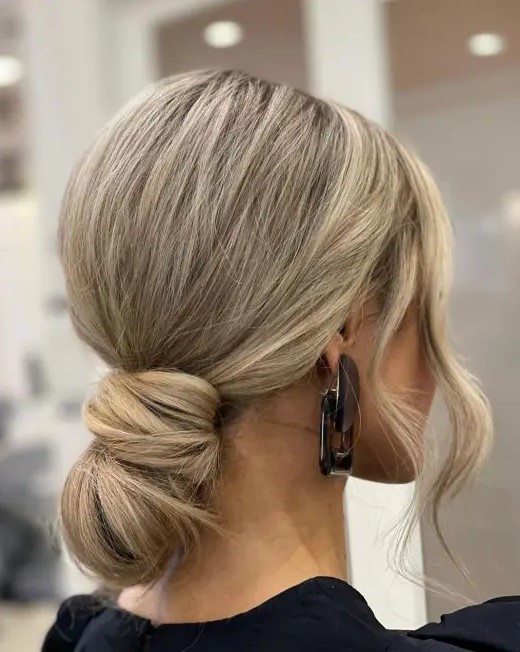 a wrapped low bun with a bump on top and some waves around the face is a super modern and chic idea
