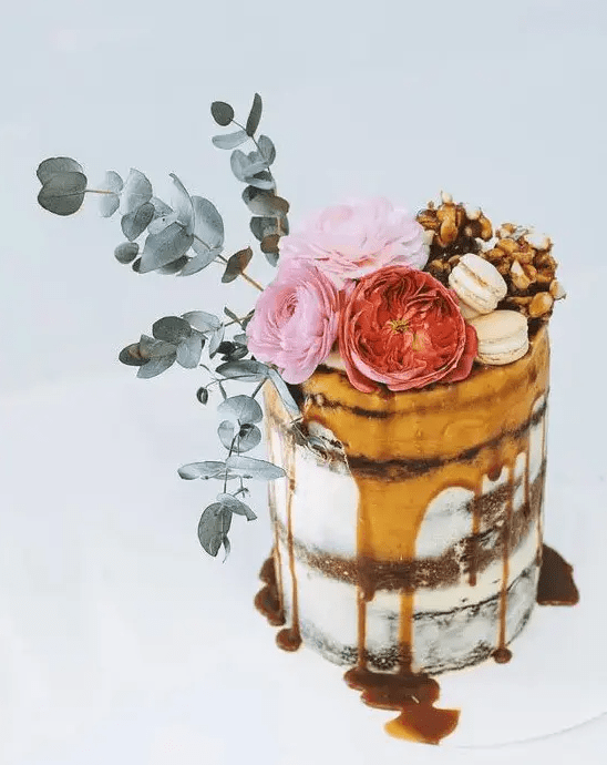 drips of salted caramel, chocolate brownie and raspberry flourless cake topped with flowers and greenery