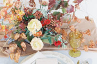 01 The wedding table setting was done with powder blue and light brown textiles, amber glasses and lush florals with fall leaves