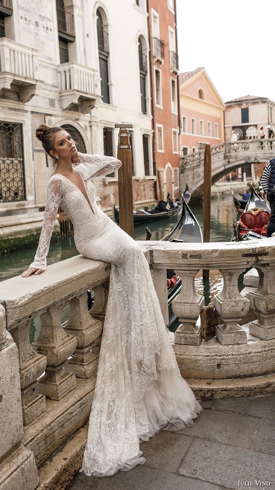 a mermaid wedding gown with a plunging neckline, lace appliques, long sleeves and embellishments by Julie Vino
