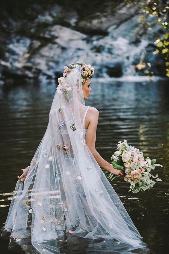 a long veil with a faux flower halo on top and pastel-colored faux blooms all over the veil