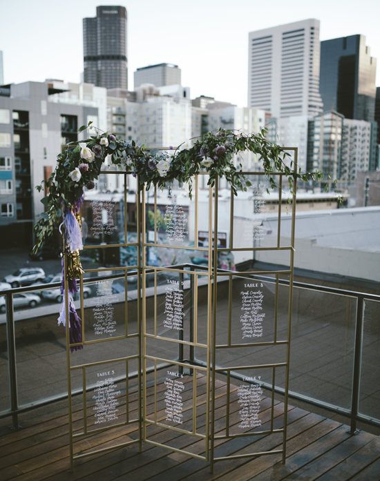 a metal frame with acrylic seatign charts and a fresh greenery garland with blooms