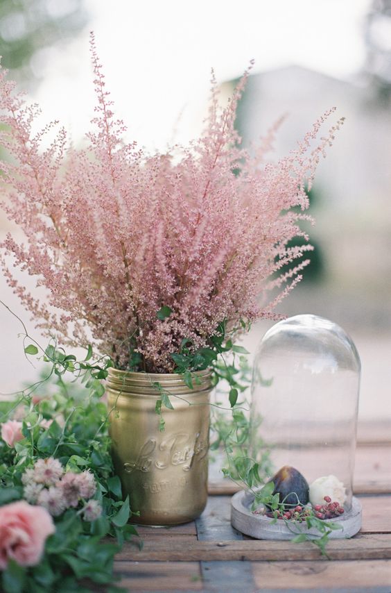 a gold mason jar with greenery and pink blooming branches