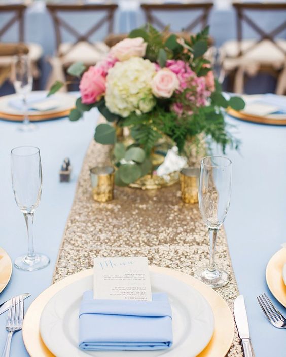 a gold sequin table runner, gold vases and candle holders, blue fabrics for a chic look