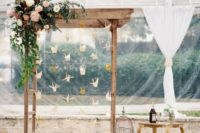 04 a wedding arch with lush greenery and blooms and hanging paper cranes, bird cages and blooms