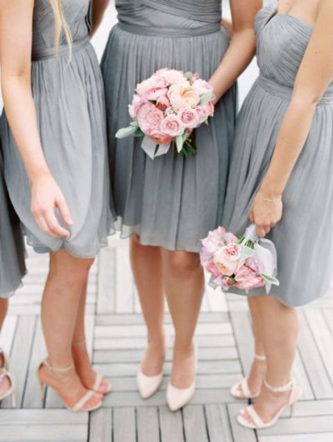 bridesmaids wearing grey strapless dresses and carrying blus rose bouquets