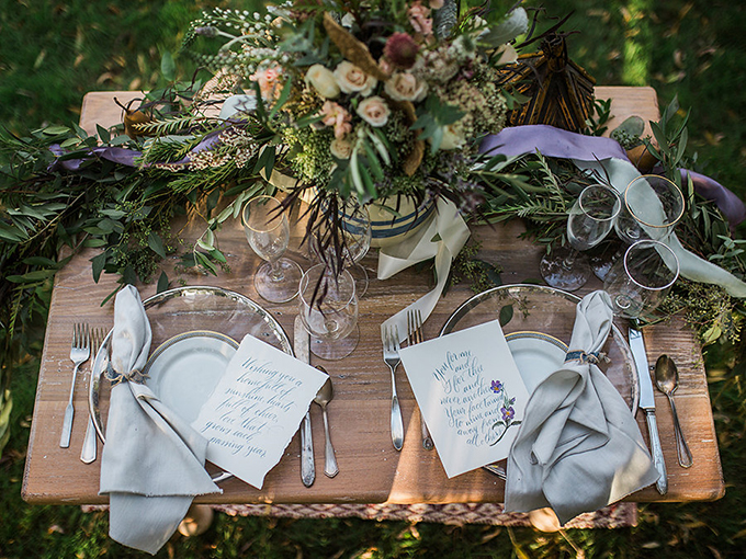 The wedding table was styled with modern sheer chargers with a metallic edge, silver flatware and lush greenery and blooms