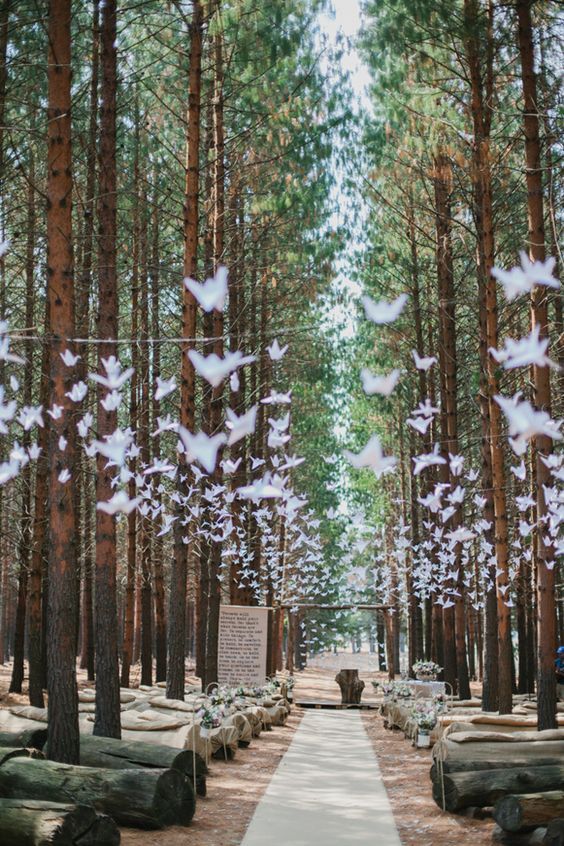 a woodland wedding ceremony space with lots of paper cranes and wooden trunks