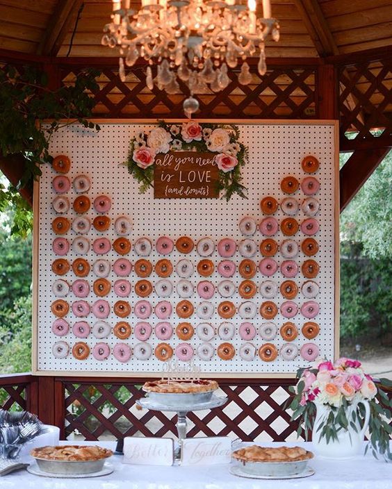 a framed pegboard donut wall topped with fresh blooms and a sign
