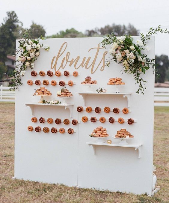 an elegant outdoor donut wall with shelves, calligraphy and fresh blooms for a chic wedding