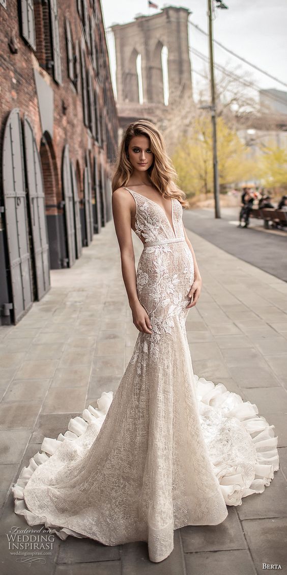 a mermaid wedding dress with lace appliques, a plunging neckline and a ruffled train by Berta