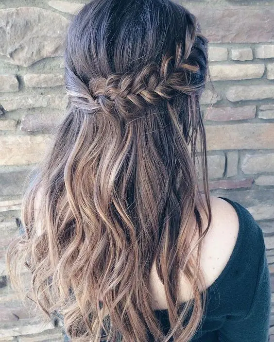 a wavy half updo with a thick fishtail braid on one side and twisted hair on the second