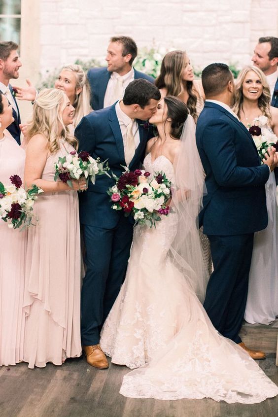 the groom and groomsmen wearing navy and the bridesmaid and bride wearing blush