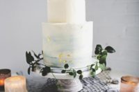 10 a light blue watercolor wedding cake with a rough edge, gold flakes and some greenery around