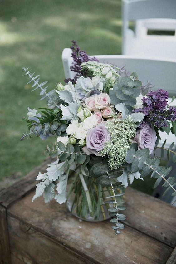 a pale wedding centerpiece with lilac and blush roses, eucalyptus, pale miller and lilac