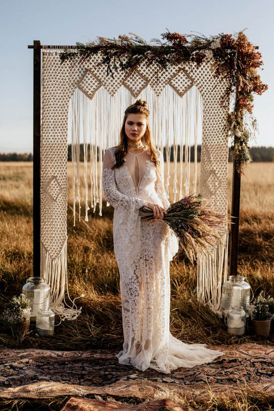 a boho lace wedding dress with a cutout on the neckline, long bell sleeves and a train
