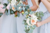 11 bridesmaids wearing light blue dresses with blush bloom bouquets