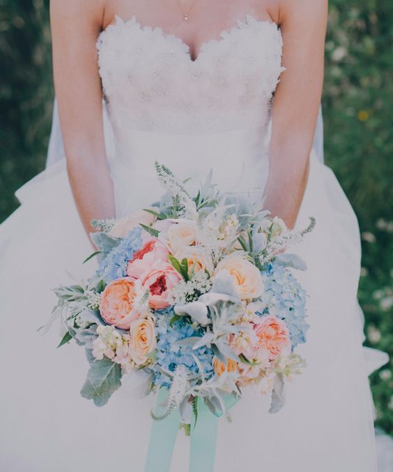 a bridal bouquet with blush, peachy pink and blue flowers for a pastel look