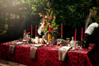 12 a pirate-inspired wedding tablescape with a printed tablecloth, a lush floral centerpiece, metallic napkins and bold candles