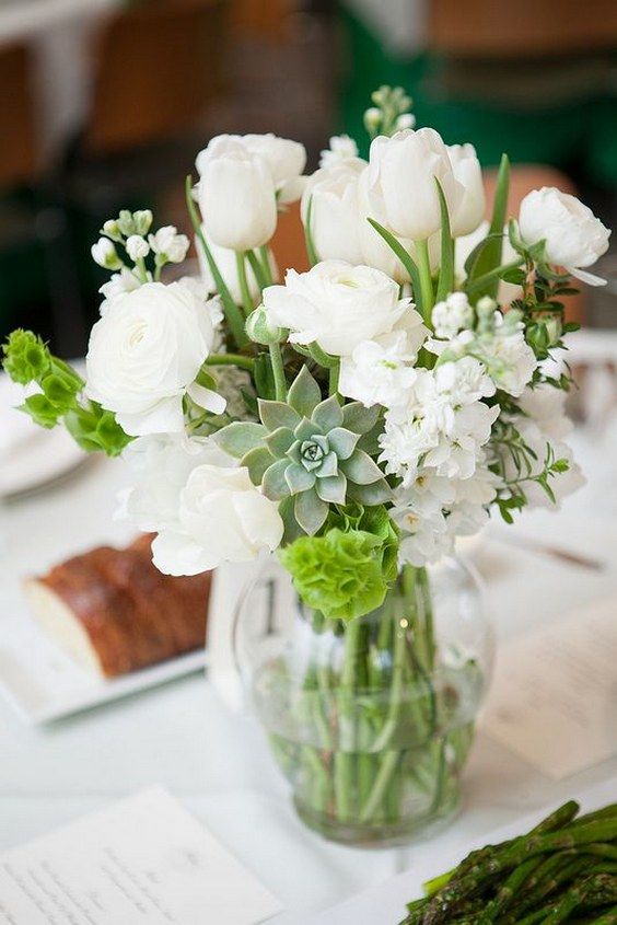 a sheer vase with white blooms, succulents and greenery