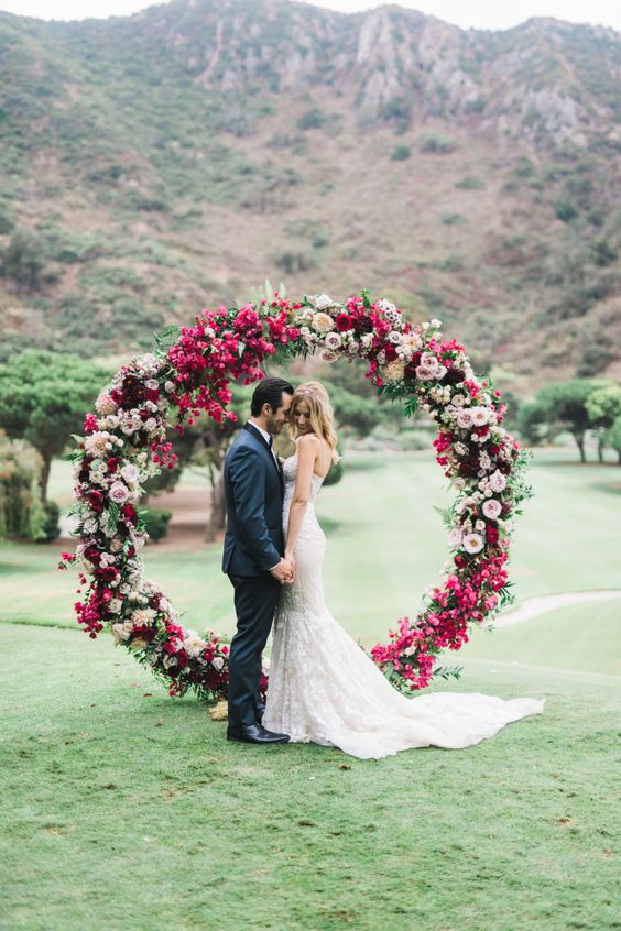 a bold fuchsia, blush and hot pink floral circle wedding arch with leaves