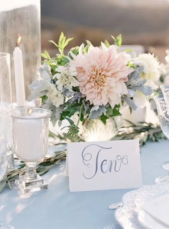 a pastel floral centerpiece with light pink and blue blooms and creamy ones
