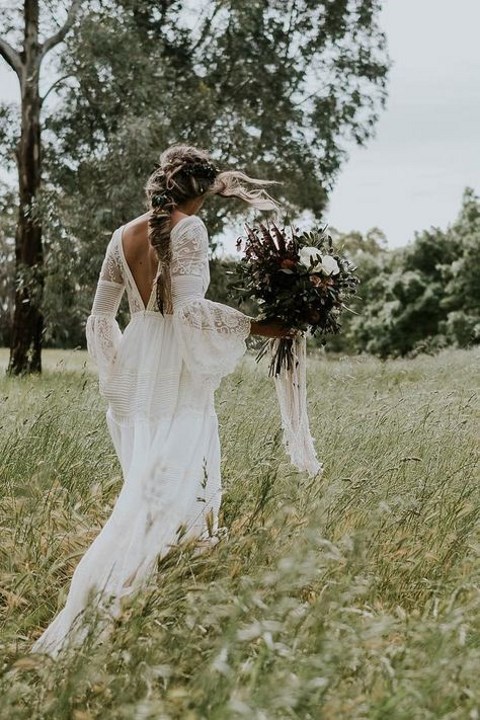 a boho lace wedding gown with bell sleeves, a cutout back and a train