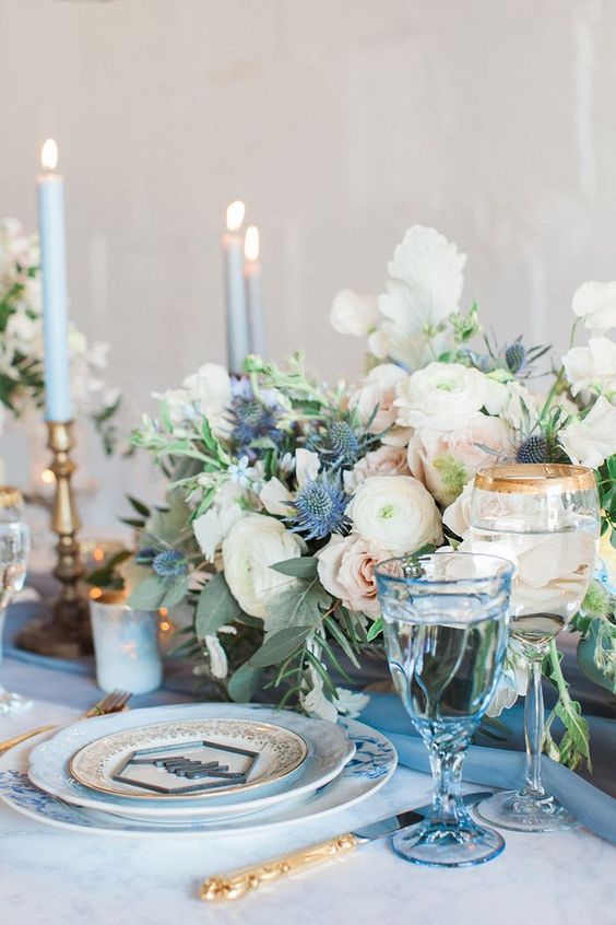 a gorgeous floral centerpiece with creamy and blush blooms plus blue thistles
