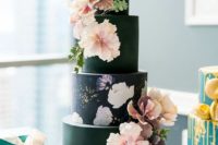 15 a black wedding cake with floral painting and blush and purple blooms on it