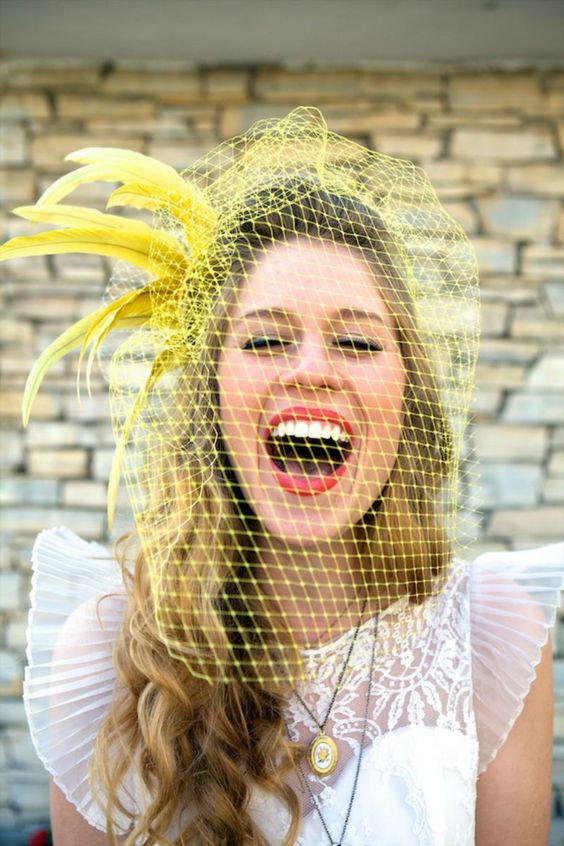 a bold yellow birdcage veil with feathers is a gorgeous idea to add fun to your look