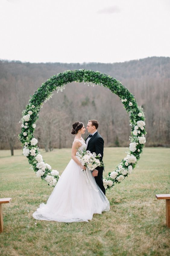 an oversized circle floral wedding arbor with lush greenery and white blooms is a very trendy solution