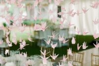 15 pink paper crane garlands hanging over the wedding reception for creating an ambience