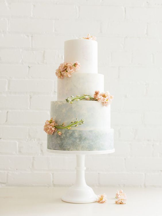 a grey watercolor wedding cake with an ombre effect and fresh peach-colored flowers for a wedding in subtle colors