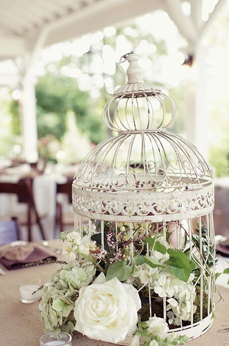 a vintage birdcage with greenery and neutral blooms for a chic centerpiece