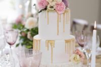 17 a wedding cake with pink and purple blooms, ruffles and gold drip