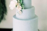 22 a light blue wedding cake with a texture and sugar flowers on top