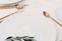 22 a minimalist tablescape with white chargers, copper cutlery, olive branches and simple menus